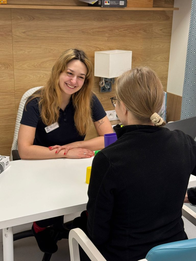 Terapia psychologiczna podczas rehabilitacji po udarze. Specjalistka rozmawia z pacjentką przy biurku w gabinecie, tworząc bezpieczną i wspierającą przestrzeń do pracy nad emocjami oraz funkcjami poznawczymi