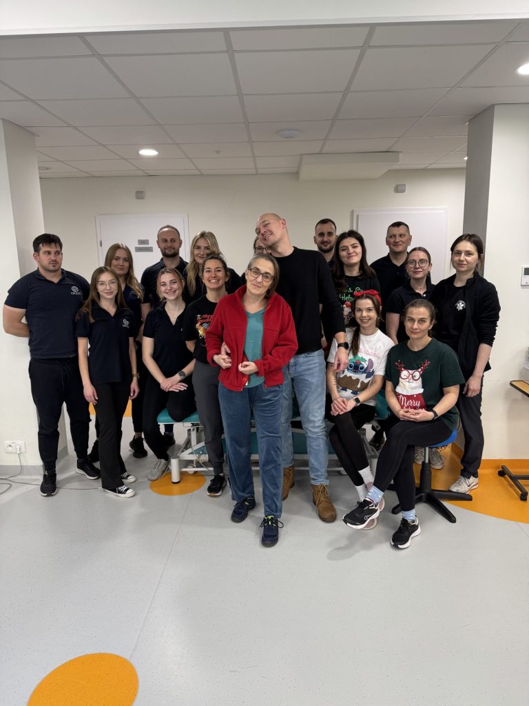 Zespół Centrum Origin Kraków w sali rehabilitacyjnej. Grupa specjalistów stoi razem do wspólnego zdjęcia, tworząc interdyscyplinarny zespół wspierający pacjentów w procesie leczenia i rehabilitacji